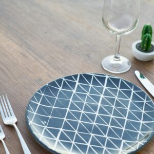 Stylish table setup with a geometric plate, silverware, and potted cactus.