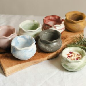 Aesthetic handmade ceramic vases displayed on a wooden board with greenery accent.