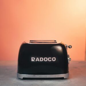 Elegant black toaster by Radoco against an inviting orange backdrop, perfect for kitchen decor.